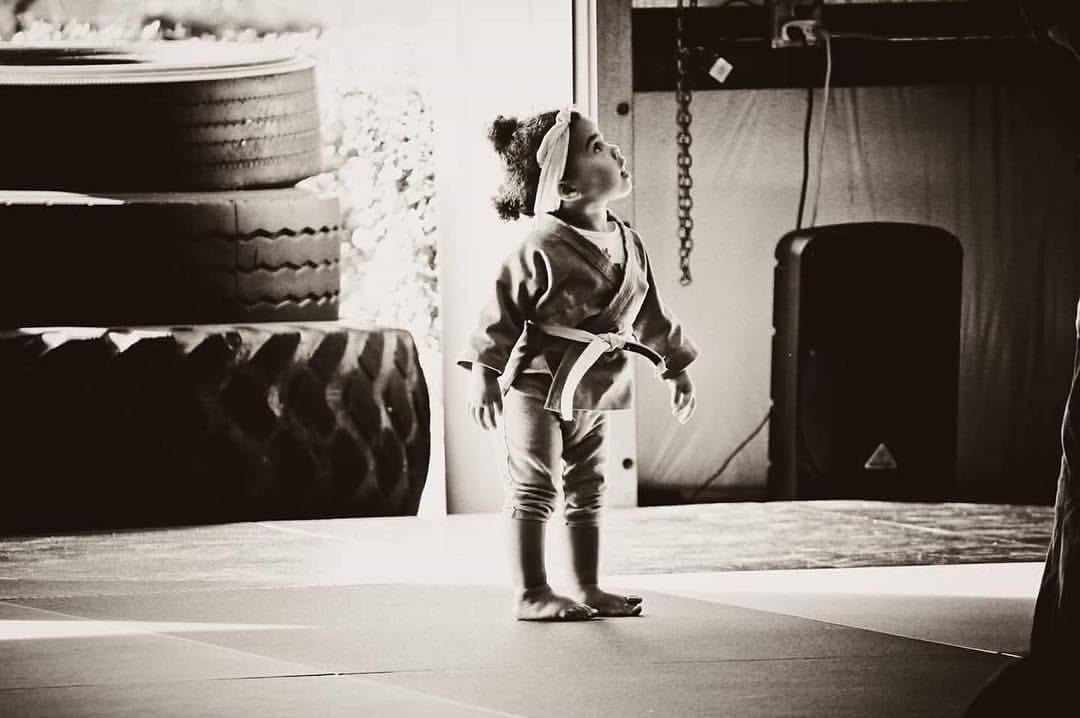 Girl on a mat in front of a training bag